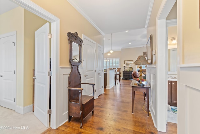 corridor with light wood-type flooring and crown molding