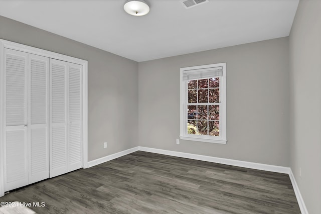 unfurnished bedroom featuring dark hardwood / wood-style flooring and a closet