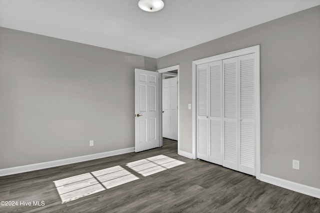 unfurnished bedroom with a closet and dark wood-type flooring