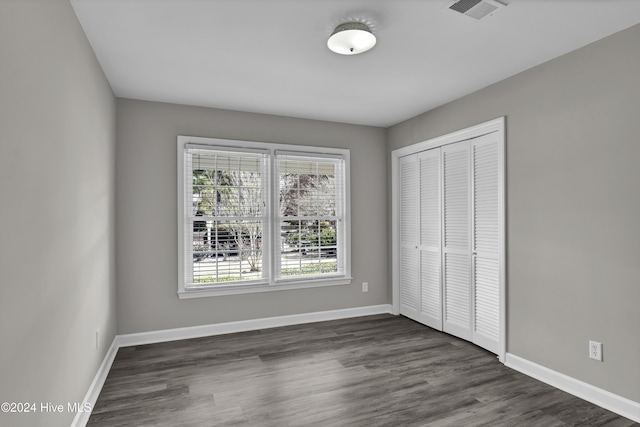 unfurnished bedroom featuring dark hardwood / wood-style flooring and a closet