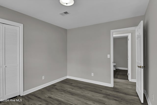 unfurnished bedroom with a closet and dark hardwood / wood-style floors