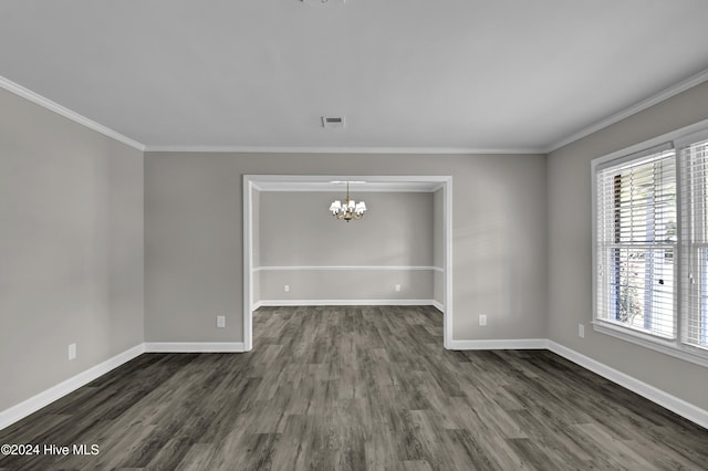 spare room featuring ornamental molding, plenty of natural light, dark wood-type flooring, and a notable chandelier