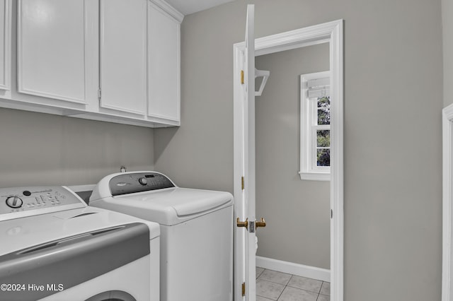 washroom featuring light tile patterned flooring, cabinets, and washing machine and clothes dryer