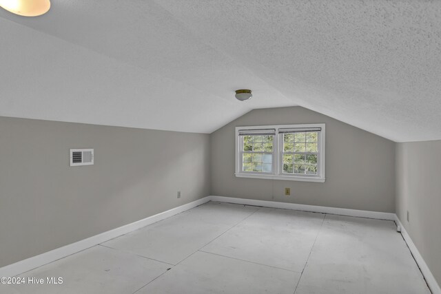 additional living space with a textured ceiling and vaulted ceiling