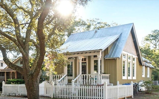 view of front of house with covered porch, a fenced front yard, and metal roof