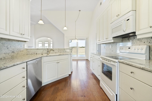 kitchen featuring white appliances, white cabinets, sink, decorative light fixtures, and dark hardwood / wood-style flooring