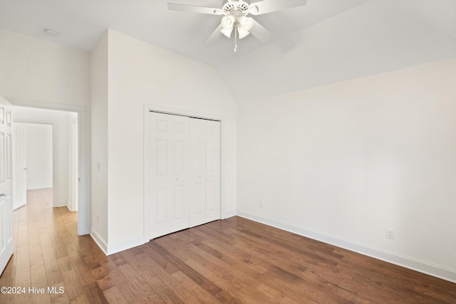 unfurnished bedroom featuring hardwood / wood-style floors, a closet, vaulted ceiling, and ceiling fan