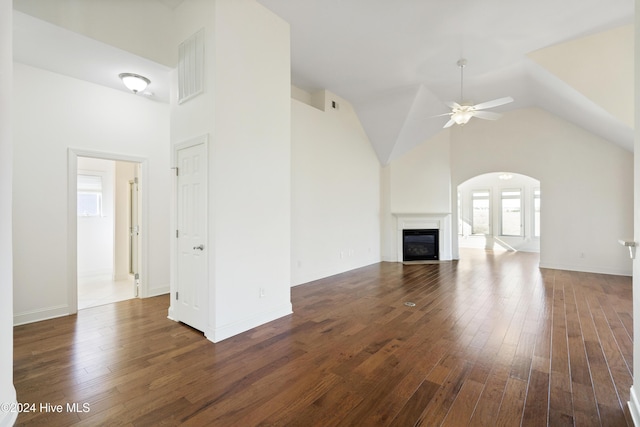 unfurnished living room featuring dark hardwood / wood-style flooring, high vaulted ceiling, and ceiling fan