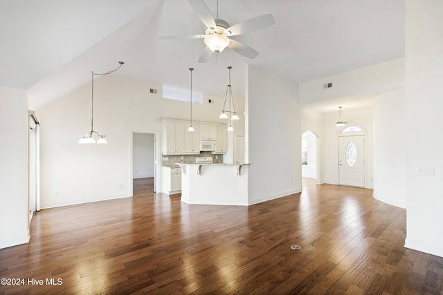 unfurnished living room featuring dark hardwood / wood-style flooring, high vaulted ceiling, and ceiling fan