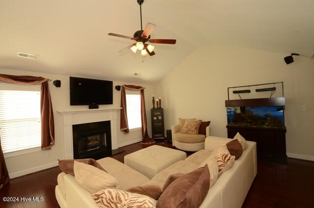 living room with ceiling fan, dark wood-type flooring, and vaulted ceiling