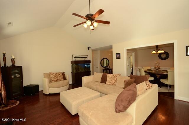 living room with dark hardwood / wood-style flooring, ceiling fan with notable chandelier, and vaulted ceiling