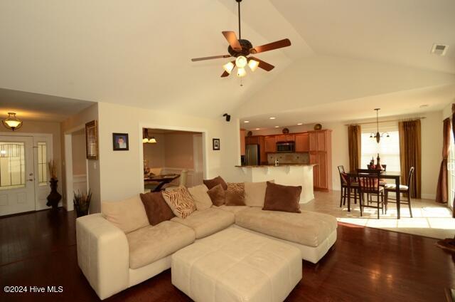 living room featuring ceiling fan, dark wood-type flooring, and vaulted ceiling