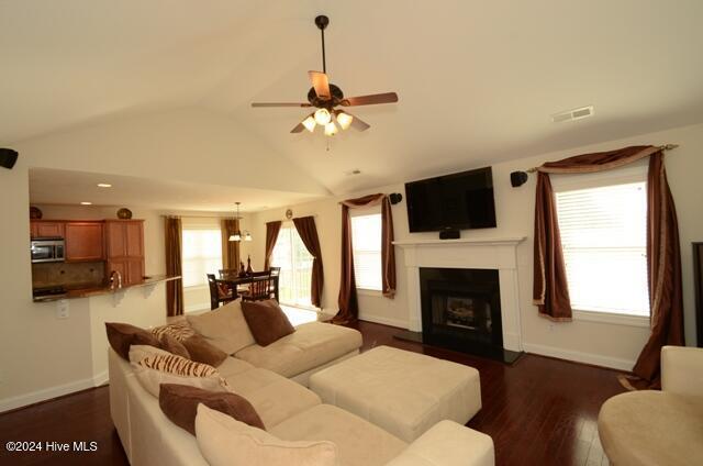 living room with dark hardwood / wood-style flooring, ceiling fan, and lofted ceiling