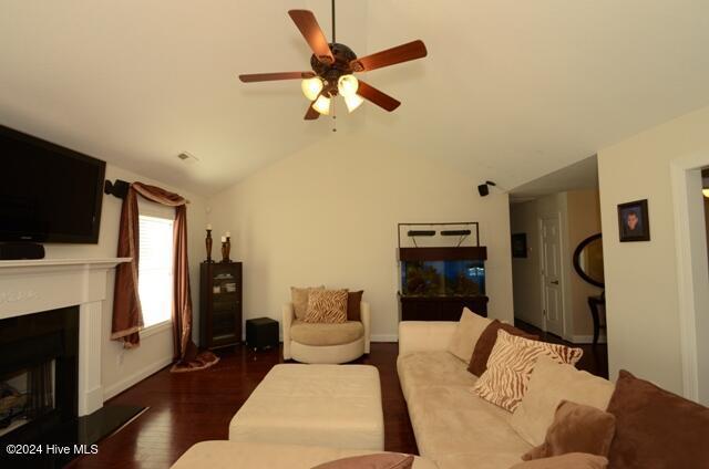 living room with dark hardwood / wood-style flooring, ceiling fan, and lofted ceiling