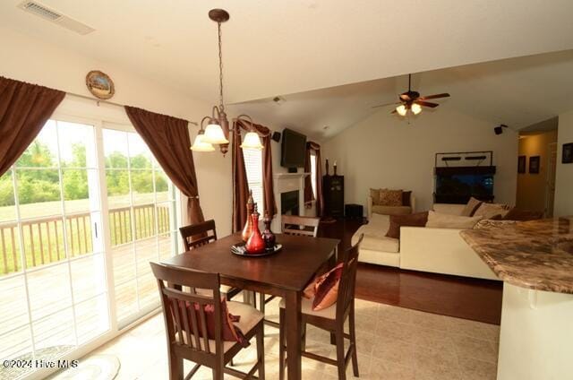 tiled dining space with ceiling fan with notable chandelier and lofted ceiling