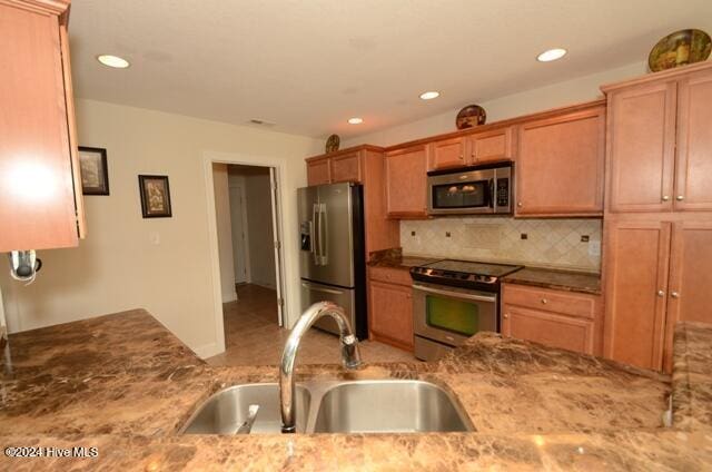 kitchen featuring sink, light stone countertops, stainless steel appliances, and tasteful backsplash