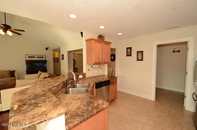 kitchen with dishwasher, ceiling fan, dark stone counters, and sink