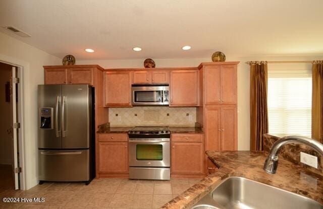 kitchen featuring decorative backsplash, light tile patterned floors, stainless steel appliances, and sink