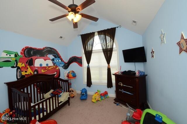 bedroom featuring a crib, carpet, vaulted ceiling, and ceiling fan