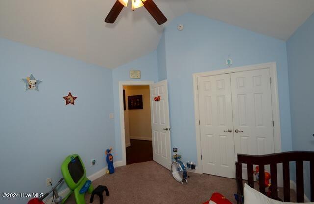 carpeted bedroom with ceiling fan, a closet, and lofted ceiling