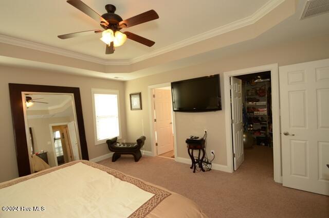 bedroom featuring carpet, a tray ceiling, ceiling fan, and crown molding