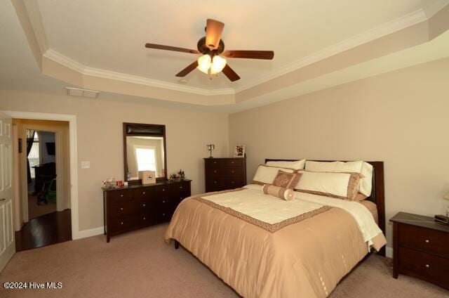 carpeted bedroom with a tray ceiling, ceiling fan, and ornamental molding