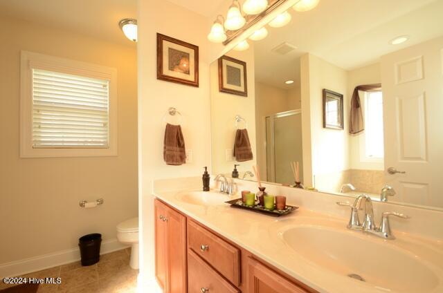 bathroom with tile patterned flooring, vanity, toilet, and a shower with door