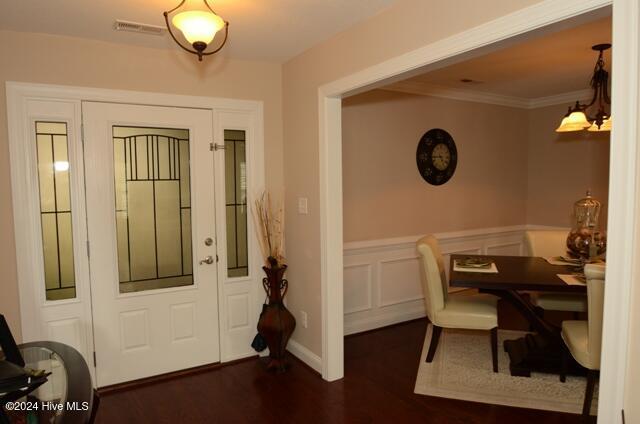 entrance foyer with dark hardwood / wood-style floors and crown molding