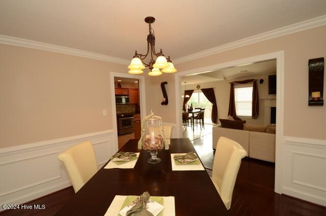 dining area with ornamental molding, dark wood-type flooring, and a notable chandelier