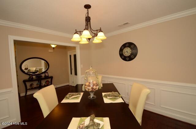 dining room with dark hardwood / wood-style floors, an inviting chandelier, and ornamental molding