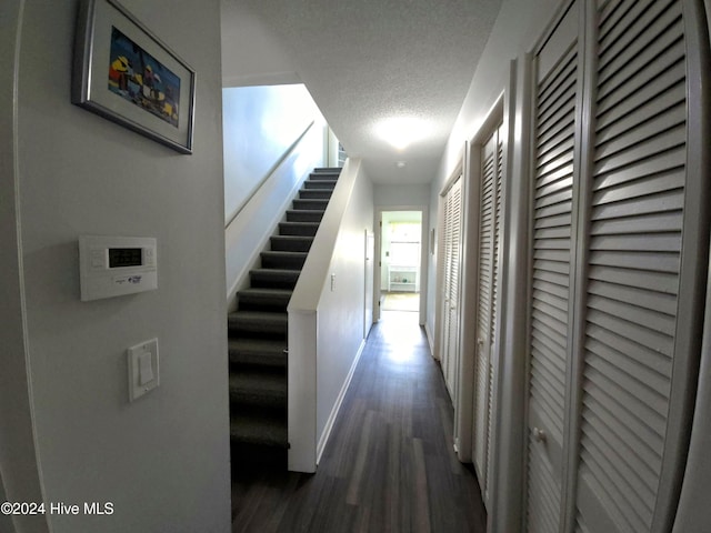 corridor with dark hardwood / wood-style flooring and a textured ceiling