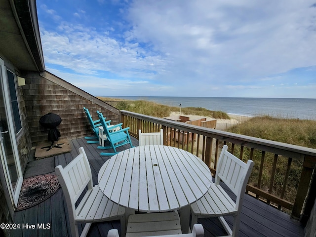 wooden terrace featuring a water view and a beach view