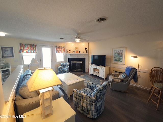 living room featuring a textured ceiling, ceiling fan, and dark hardwood / wood-style floors