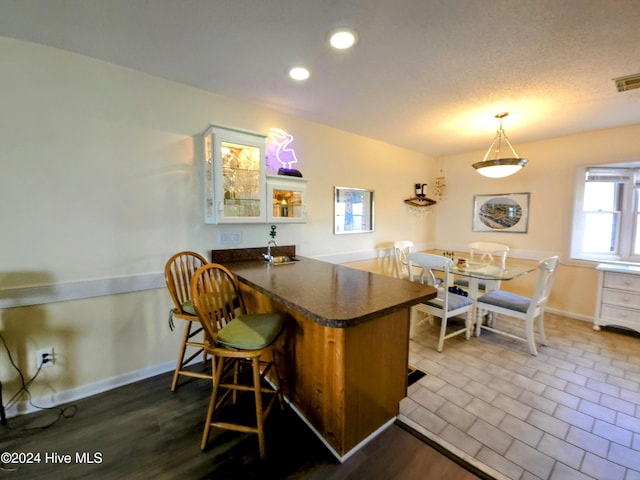 kitchen with pendant lighting, light hardwood / wood-style floors, white cabinetry, and kitchen peninsula