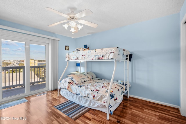 bedroom with ceiling fan, dark hardwood / wood-style flooring, a textured ceiling, and access to outside