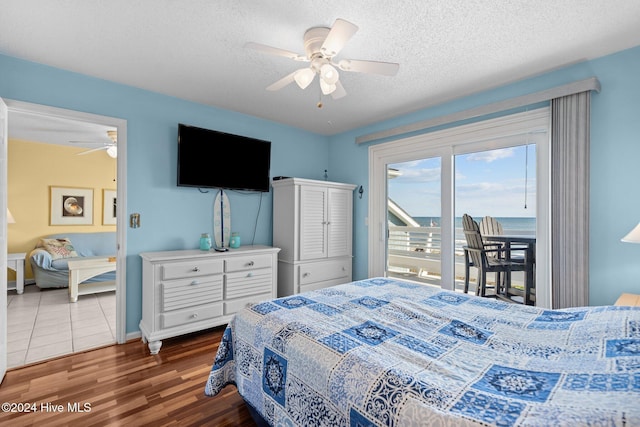 bedroom featuring dark hardwood / wood-style floors, ceiling fan, access to exterior, and a textured ceiling