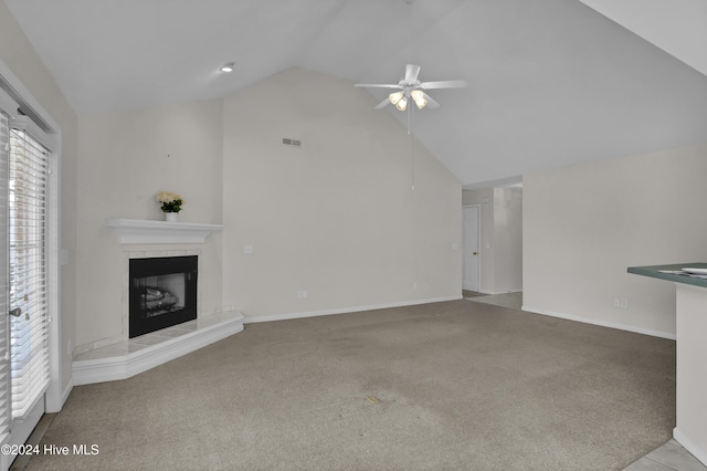 unfurnished living room featuring a high end fireplace, light colored carpet, vaulted ceiling, and ceiling fan