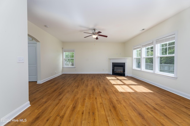 unfurnished living room featuring wood-type flooring, plenty of natural light, and ceiling fan