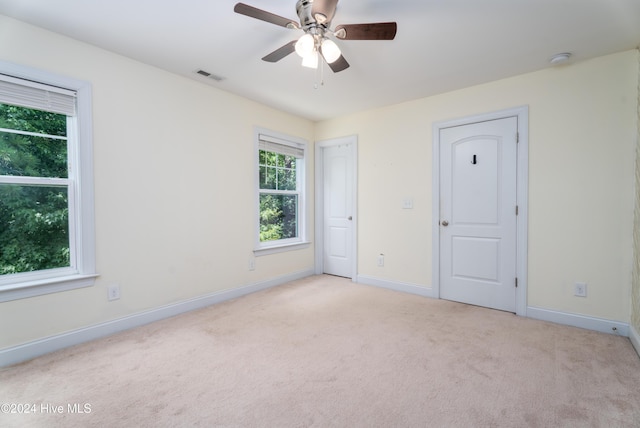 unfurnished bedroom with ceiling fan, light carpet, and multiple windows