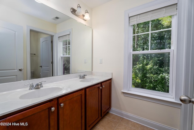 bathroom with tile patterned flooring, vanity, toilet, and a healthy amount of sunlight