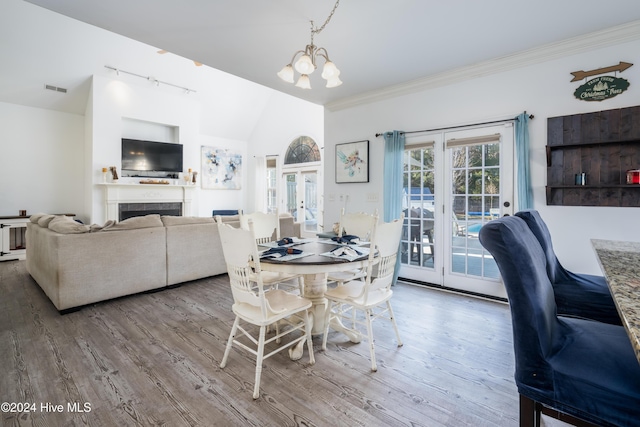 dining space with lofted ceiling, wood-type flooring, french doors, and a chandelier