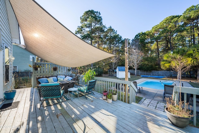 deck featuring a shed, an outdoor living space, and a covered pool