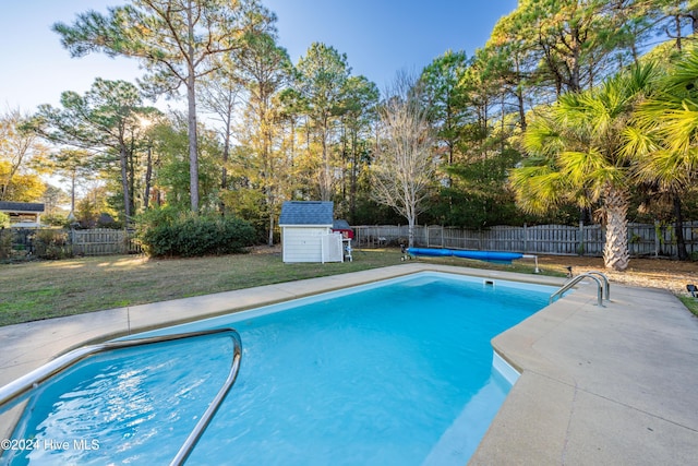 view of pool featuring a lawn and a storage unit