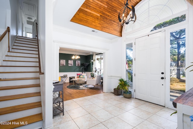 foyer with a chandelier, light wood-type flooring, crown molding, and a healthy amount of sunlight