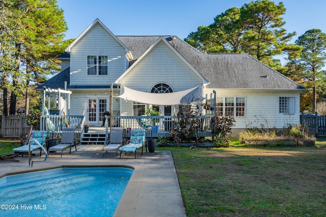 back of property with a swimming pool side deck and a yard