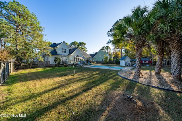 view of yard featuring a fenced in pool and a shed