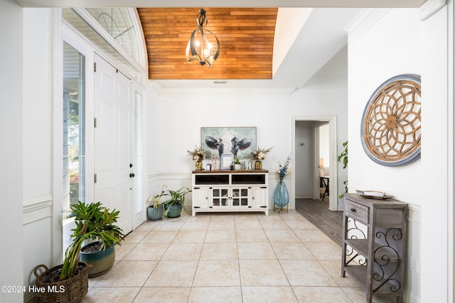 foyer featuring light tile patterned flooring, ornamental molding, and wood ceiling