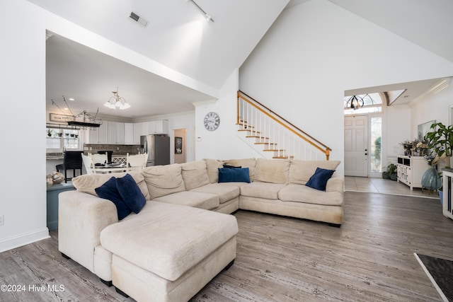 living room with high vaulted ceiling, a notable chandelier, and hardwood / wood-style flooring