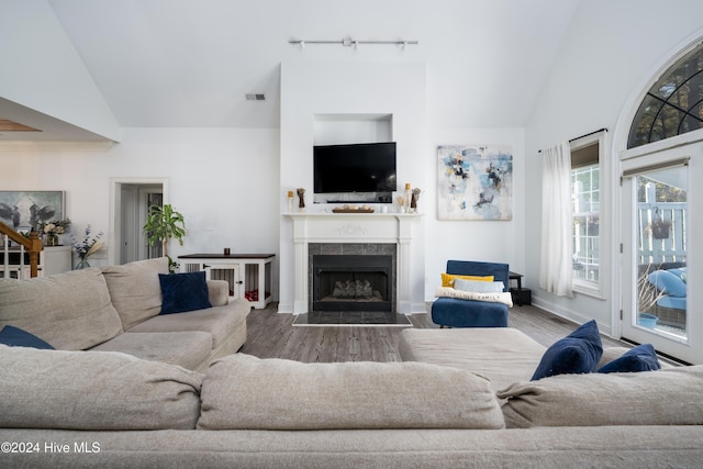 living room with a tile fireplace, high vaulted ceiling, and wood-type flooring