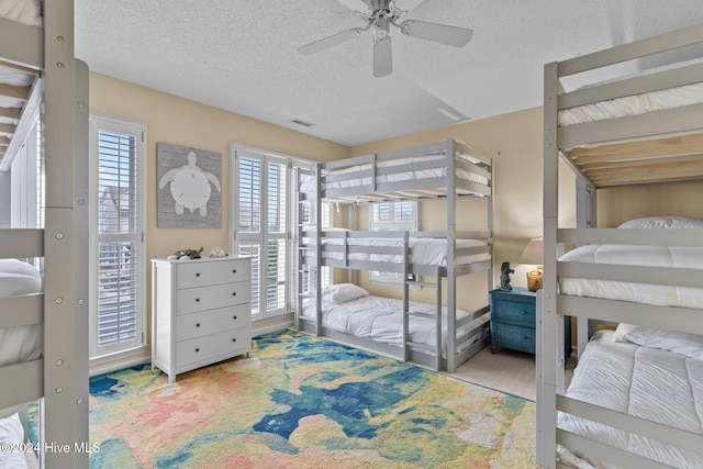 carpeted bedroom with multiple windows, ceiling fan, and a textured ceiling